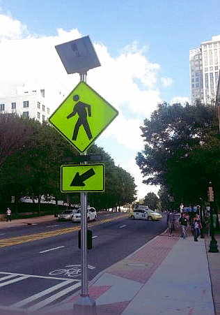 A street with solar powered pedestrian crosswalk signs